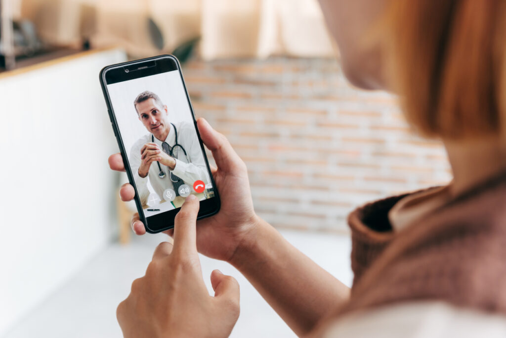 Young woman meet her doctor via video call by smart phone at home, while covid-19 out break.