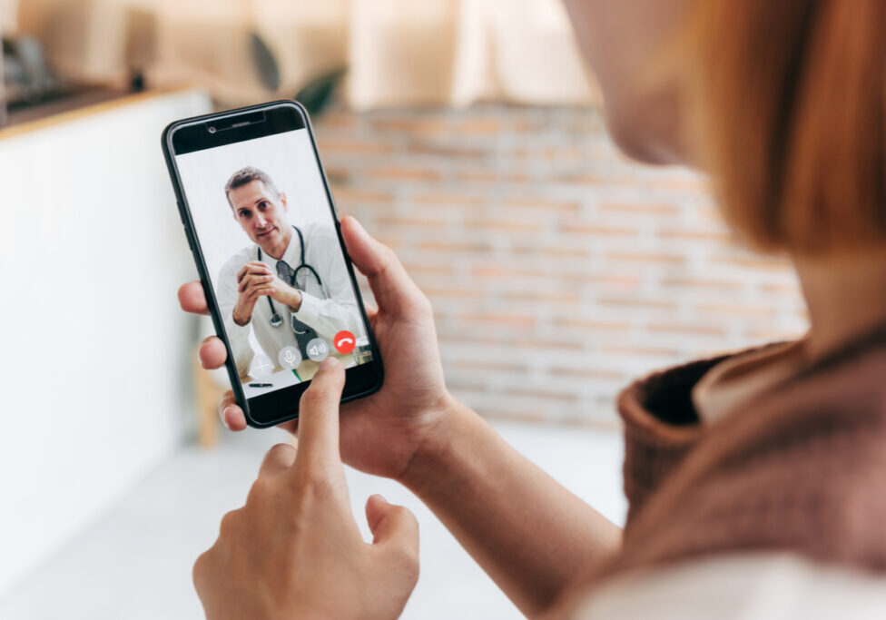 Young woman meet her doctor via video call by smart phone at home, while covid-19 out break.